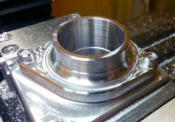 Here's one of the finished throttle body adapters, still mounted on the fixture. Looks just like the rendering above! 